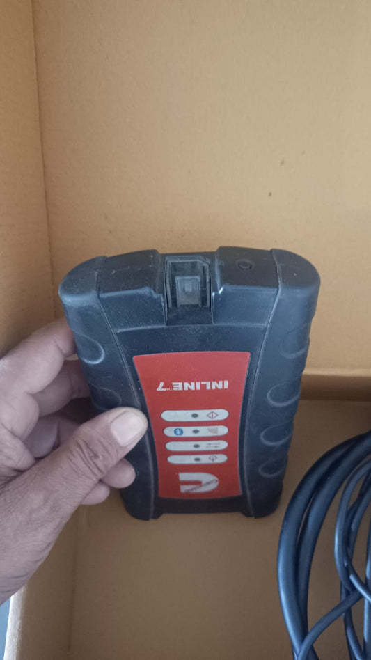 Hand holding a black and red Inline7 battery pack against a beige wall.
