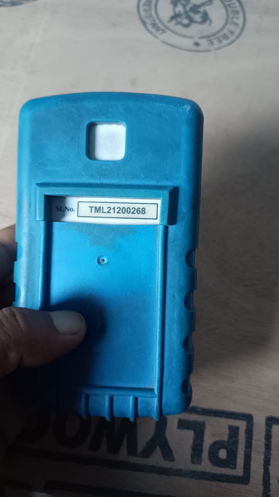 Blue tool box with a label held by a hand on a textured surface