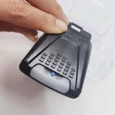 Hand holding a small electronic device with keypad on a white background